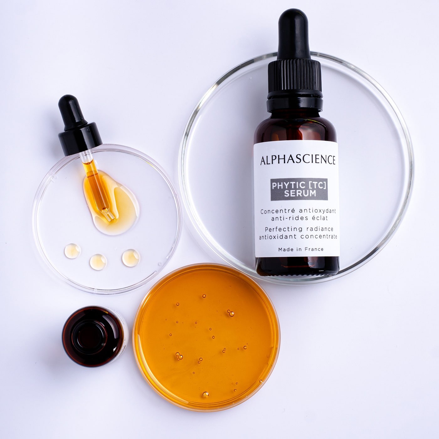 Sérum transparent au bout d'un doigt, à côté d'une pipette de verre. | Clear serum pooled on a fingertip beside a glass pipette.